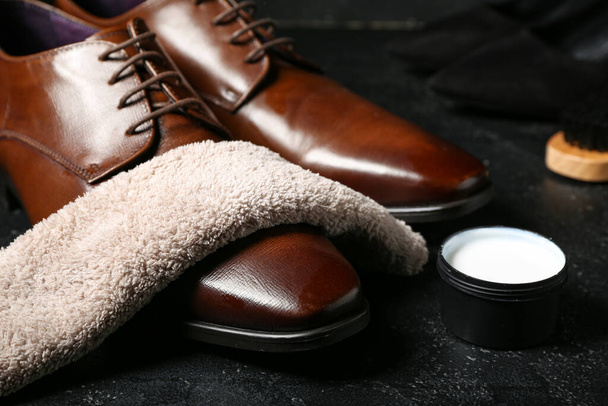 Zapatos de cuero brillante, paño, pincel y esmalte de zapatos sobre fondo negro - Foto, Imagen