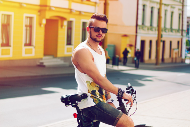 Jonge hipster man met fiets in de stad in zonnige zomerdag - Foto, afbeelding
