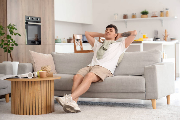 Junger Mann ruht auf Sofa in Küche - Foto, Bild
