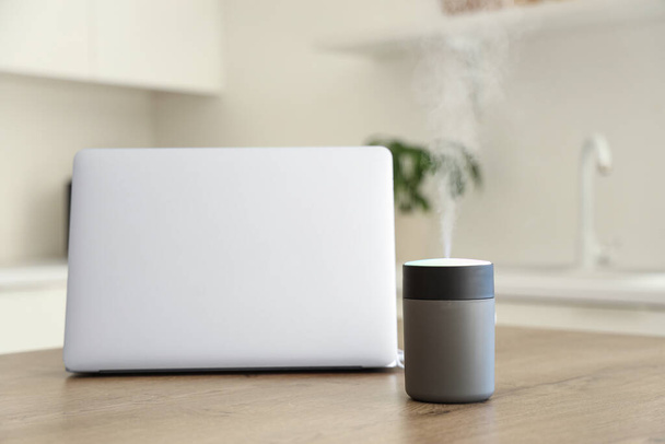 Air humidifier with laptop on table in kitchen, closeup - Photo, Image