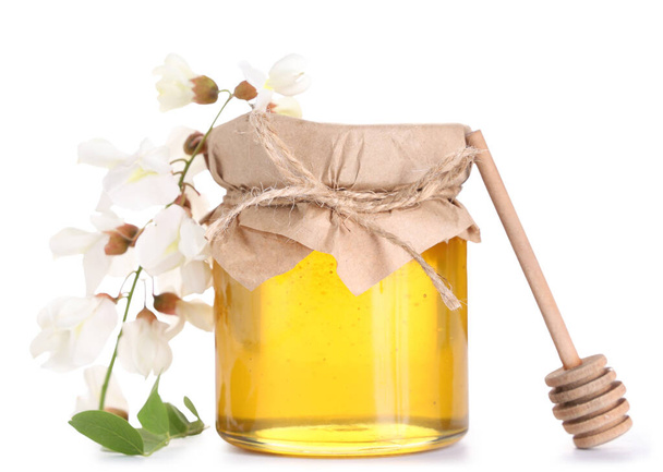 pot zoete honing met acacia bloemen en dipper op witte achtergrond - Foto, afbeelding