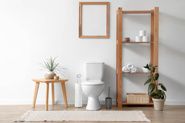 Interiér toalety s WC mísou, konferenčním stolkem a regálovou jednotkou v blízkosti bílé stěny - Fotografie, Obrázek