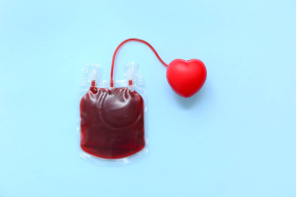 Blood pack with red heart on blue background. World Blood Donor Day - Photo, Image