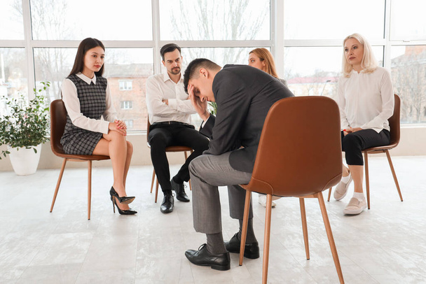 Upset business man sitting at group therapy session - Фото, изображение