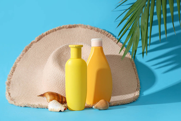 Bouteilles de crème solaire, chapeau de paille et coquillages sur fond de couleur - Photo, image