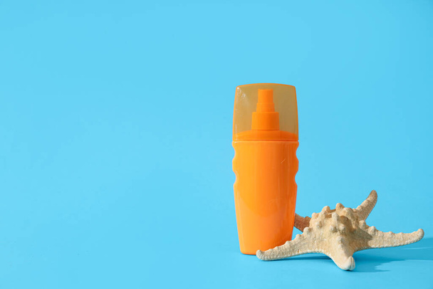 Botella de crema protector solar y estrellas de mar sobre fondo de color - Foto, imagen