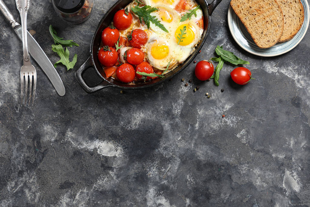 Обсмажуємо сковороду зі смачними яйцями, помідорами, спеціями та хлібом на гранжевому фоні - Фото, зображення