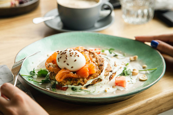 Vegetarische Zucchini-Pfannkuchen mit pochiertem Ei, Lachs und Tomaten aus nächster Nähe, gesundes Frühstück, Draufsicht. - Foto, Bild