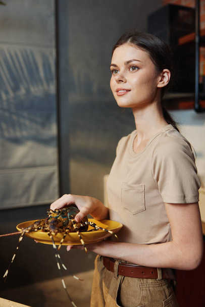 Μια γυναίκα ετοιμάζει νόστιμο σπιτικό γεύμα σε ένα άνετο εστιατόριο κουζίνα, κρατώντας ένα πιάτο φρεσκομαγειρεμένο φαγητό - Φωτογραφία, εικόνα