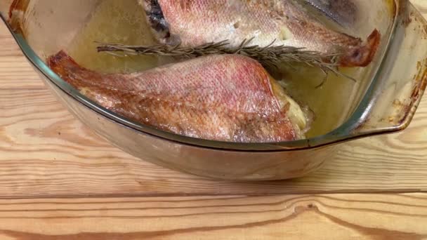 Запеченные красные рыбы в старом стеклянном блюде для выпечки на деревенском столе - Кадры, видео