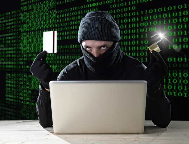 kredi kartı ve banka hesabı parolası kesmek suç faaliyeti için bilgisayar dizüstü kullanarak kilit tutan siyahlı adam - Fotoğraf, Görsel