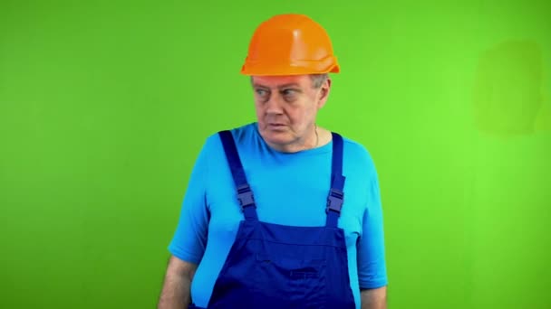 Repairman in overalls puts fingers to lips and says shhh demanding silence. Mature worker demanding shut up and waving his finger in negative. Green screen. Chroma key. - Footage, Video