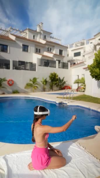 Una mujer está disfrutando pacíficamente del sol en una piscina del resort mientras usa un auricular VR para una experiencia de realidad virtual - Imágenes, Vídeo