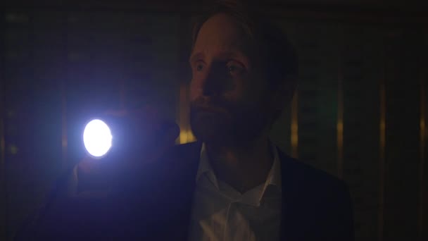 Un homme explore une pièce faiblement éclairée avec une lampe de poche, créant une lueur étrange alors qu'il enquête sur l'inconnu - Séquence, vidéo