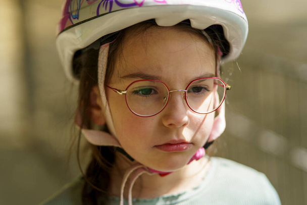 Petite fille mignonne et triste cycliste portant des lunettes et un casque - Photo, image