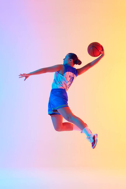 Mladá atletická žena, basketbalista dělá perfektní slam ponořit v pohybu v neonovém světle na gradient studio pozadí. Koncept sportu, mistrovství, turnaje, hobby a rekreace. Reklama - Fotografie, Obrázek