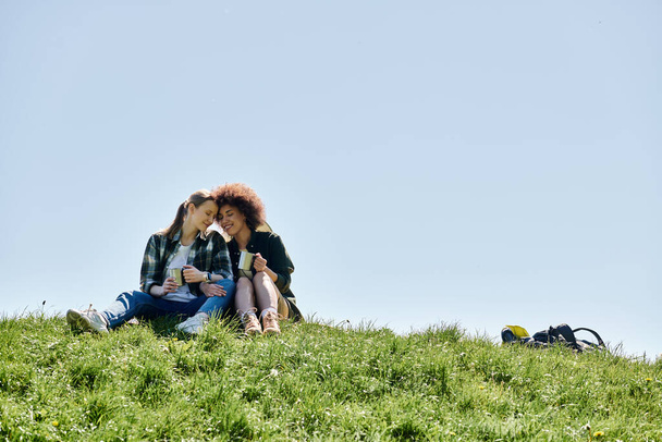 多文化レズビアンカップルは,荒野で晴れた日ハイキングを楽しんで,休憩中に親密さの瞬間を共有しています. - 写真・画像