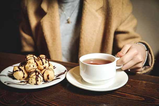 Egy személy ül az asztalnál, és élvezi az ételt, amely egy tál ételből és egy csésze teából áll. - Fotó, kép