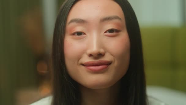Портрет крупным планом азиатская японка 20-х лет ген з девушка молодая студентка деловая женщина китаянка корейка покупательница азиатка красотка счастливые эмоции веселая улыбка глядя в камеру головной убор в помещении - Кадры, видео