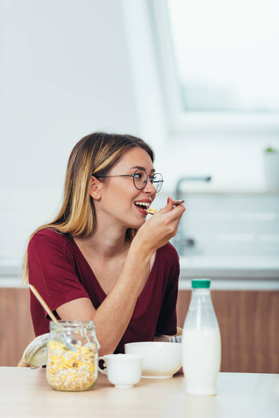 Shot van een aantrekkelijke jonge vrouw genietend van een gezond ontbijt in de keuken - Foto, afbeelding