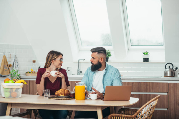 Young beautiful couple having a breakfast at home while drinking coffee - Photo, Image