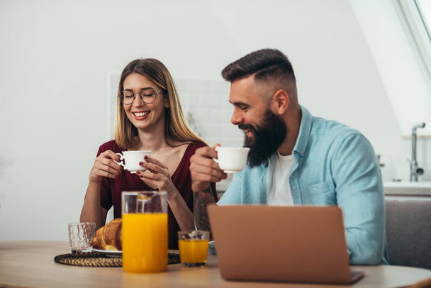 幸せな若いカップルのショット自宅でキッチンで朝食とコーヒーを楽しむ - 写真・画像