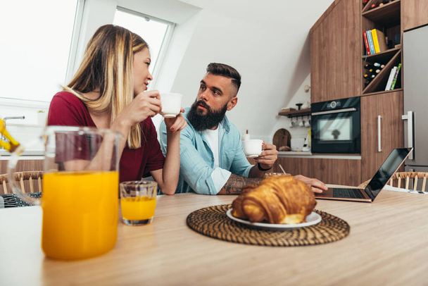 Aufnahme eines lächelnden jungen Paares beim Frühstück in der heimischen Küche - Foto, Bild