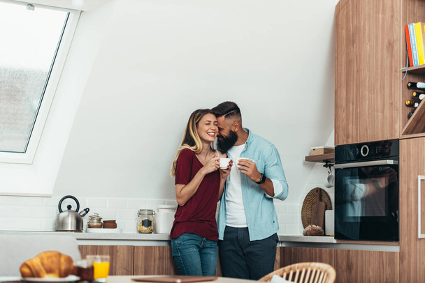 若いロマンチックなカップルのショットは、自宅でキッチンで一緒にコーヒーブレイクを楽しんで - 写真・画像