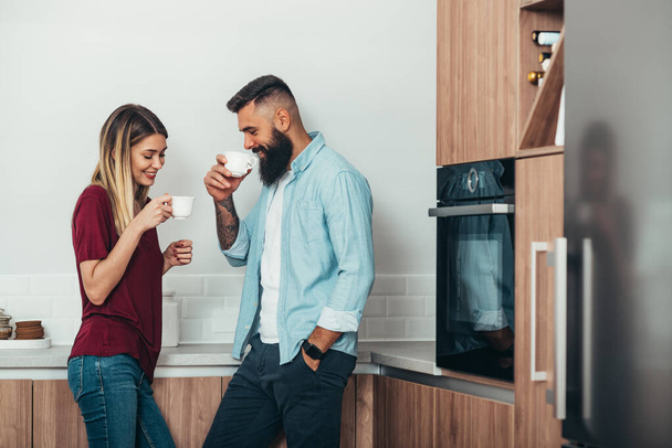 Shot na mladý pár těší relaxační přestávka na kávu v kuchyni doma - Fotografie, Obrázek