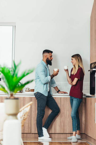 Aufnahme eines glücklichen jungen Paares, das in der Küche Kaffee trinkt und Zeit miteinander zu Hause verbringt - Foto, Bild