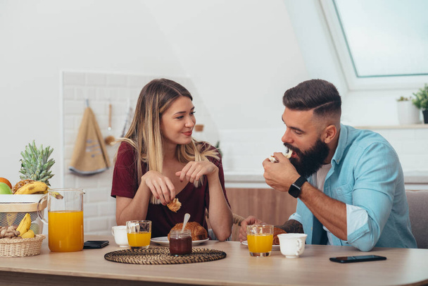 Young couple in love having breakfast in the kitchen at home - Photo, Image