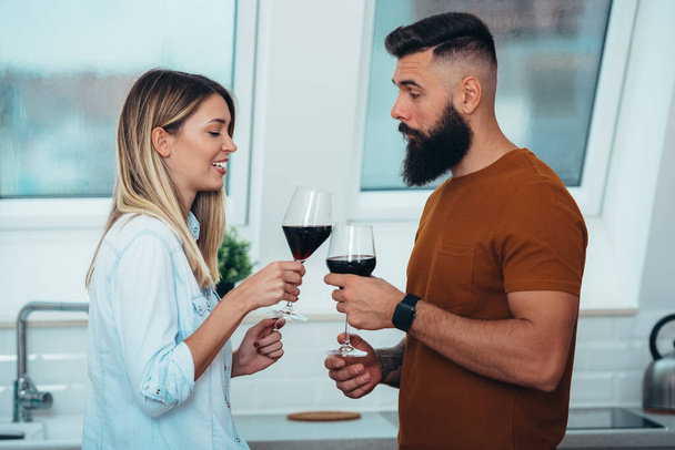 Зграя щасливої молодої пари, яка під час пиття вина об "єднує свій новий дім. - Фото, зображення
