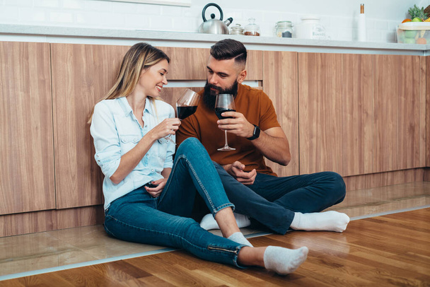 Kaunis pari ottaa romanttinen päivämäärä juodessaan viiniä keittiössä kotona - Valokuva, kuva