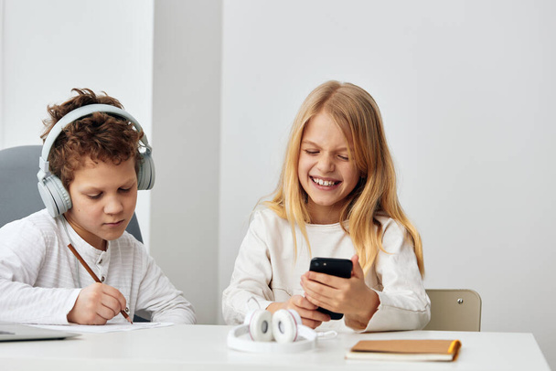 Szczęśliwe rodzeństwo kaukaskie studiuje razem w domu, używa laptopów i słuchawek do elearningu Siedzą przy stole w salonie, w pełni skoncentrowani na swojej technologii edukacji online - Zdjęcie, obraz