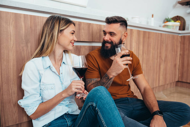 Mooi koppel dat een romantisch afspraakje heeft terwijl ze thuis wijn drinken in de keuken - Foto, afbeelding