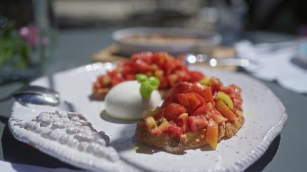 Bruschetta apetitosa com tomate fresco e mussarela em um prato branco ao ar livre, capturando a essência do jantar ao ar livre e cozinha italiana. - Filmagem, Vídeo