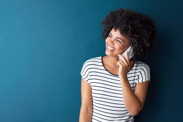 African woman, phone call and smile in studio by space for mockup, thinking or contact by blue background. Person, girl and smartphone with conversation, listening or happy for chat on mobile network. - Foto, Imagen