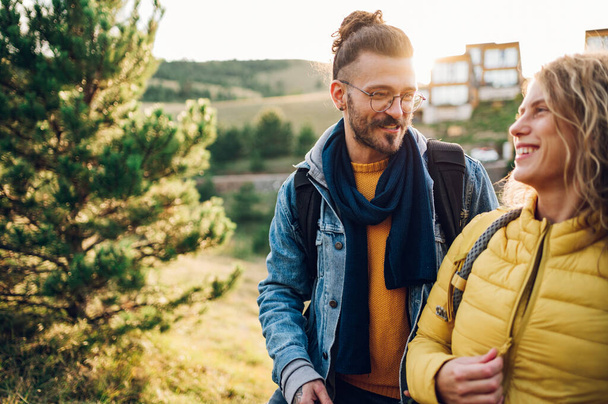Portrait of a happy couple follow trail along grassy mountain ridge and having fun together while walking in the nature. Healthy lifestyle and romantic getaway. Focus on a man with eyeglasses. - Photo, Image