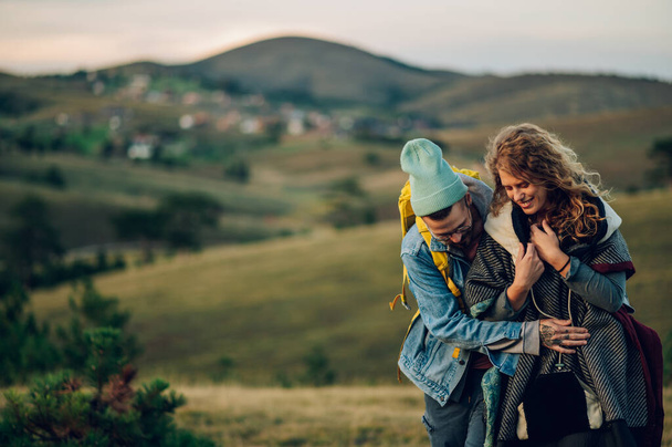 Sorridente giovane coppia felice divertirsi sul loro viaggio di trekking mentre si abbracciano e camminare insieme su un sentiero di montagna. Coppia di escursionisti caucasici che si divertono in vacanza. Copia spazio. - Foto, immagini