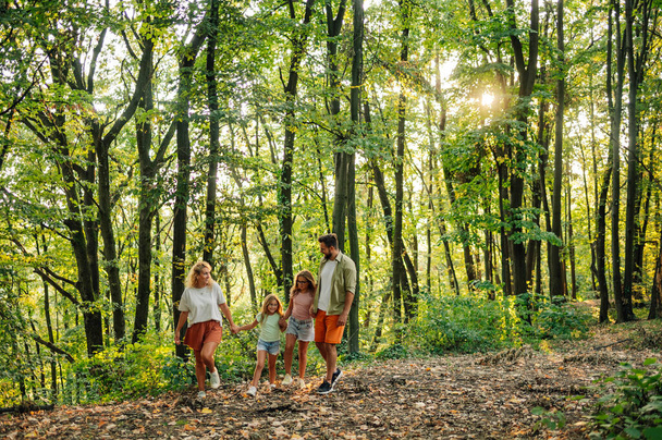 Повна тривалість щасливої сім'ї, яка гуляє на природі і досліджує ліс, проводячи вихідні і вільний час на природі. Сім'я тримається за руки і гуляє по лісу. Копіювати простір. - Фото, зображення