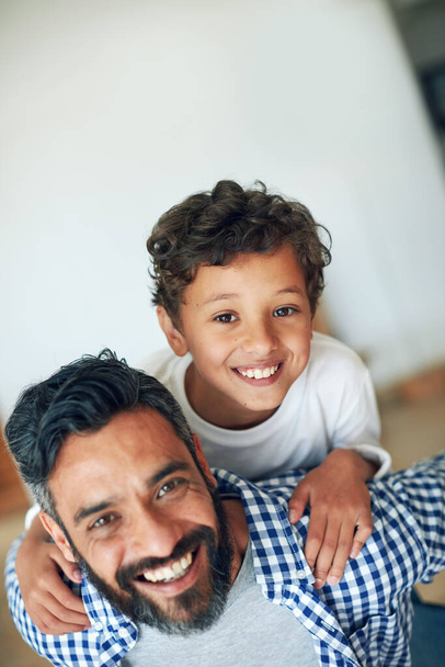 Family, piggy back and portrait of father with child in home for bonding, love and relationship in living room. Parents, happy and dad with boy in house for playing, childhood and relaxing on weekend. - Photo, Image
