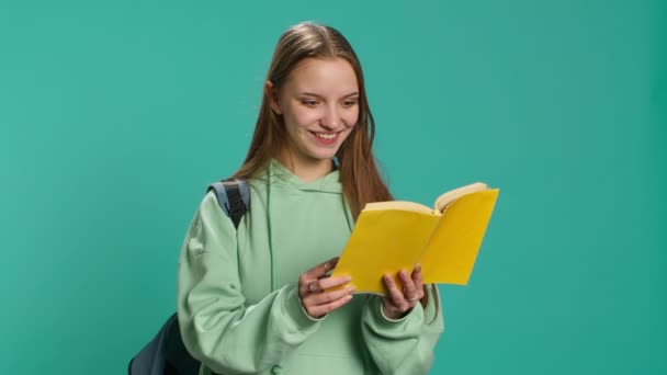 Femme adolescente avec le livre dans les mains montrant l'appréciation pour la littérature, isolé sur fond de studio. Jeune passionné de lecture tenant roman, appréciant la lecture passe-temps, caméra A - Séquence, vidéo
