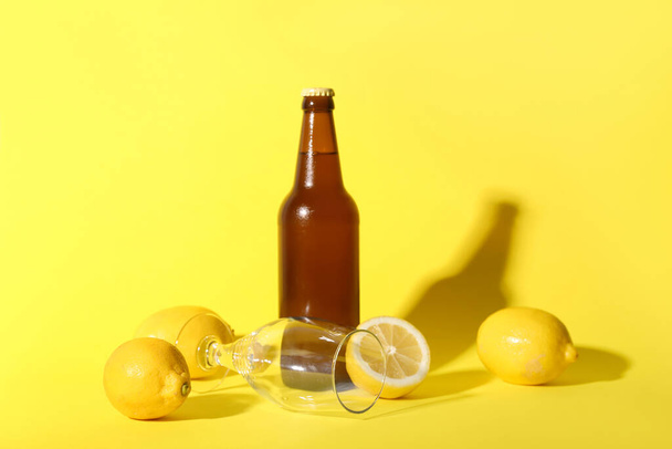 Sarı arka planda limonlu bir şişe taze bira. - Fotoğraf, Görsel