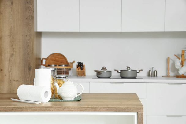 Рулони паперових рушників з чайником і їжею на столі на кухні - Фото, зображення