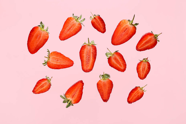 Fliegende Hälften süßer Erdbeeren auf rosa Hintergrund - Foto, Bild
