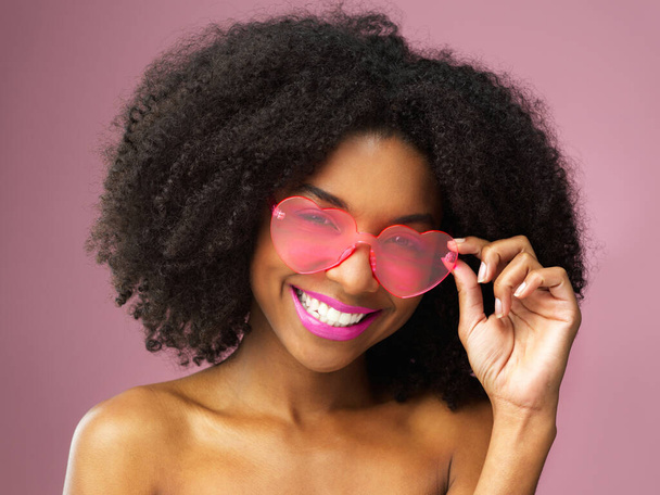 Woman, portrait and face of curly hair, sunglasses and skincare for playful person isolated on color background. Smile, dermatology and fashion for beauty with female model in studio for haircare. - Photo, Image