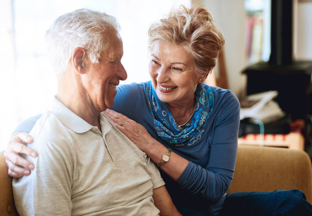 Couple, senior and smile with love on sofa at house, living room and bonding with hug for care together. Happy, woman and man in marriage for healthy relationship with trust, support and retirement. - Photo, Image