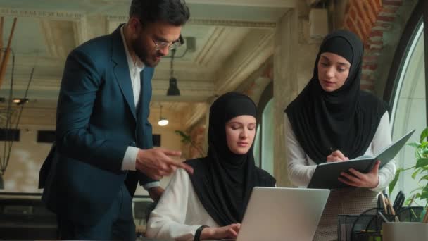 Három munkatárs kollégák üzletember üzletembernők együtt dolgoznak arab férfi muszlim nők hidzsáb férfi női csapatmunka megvitatják talk írása laptop üzleti projekt irodai cég - Felvétel, videó