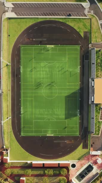Pantalla vertical: Una cautivadora vista aérea de un campo de fútbol con una pista de atletismo, capturada en alta resolución en una pantalla vertical. Incluye luces del estadio, pistas y una escena deportiva moderna - Metraje, vídeo