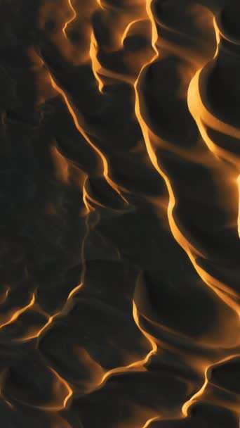 Schermo verticale: Un video verticale aereo mozzafiato che mostra i modelli ipnotizzanti e le texture delle dune di sabbia illuminate dalla luce calda del sole al tramonto, creando paesaggi ombreggiati dinamici. - Filmati, video